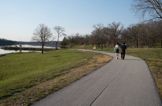 Paved lakeside path and benches at Lake Olathe in early spring